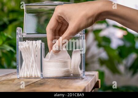 la mano della donna tira fuori un tampone di cotone bianco dal primo piano dell'organizer Foto Stock