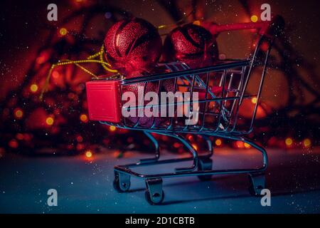 Carrello con palline di Natale rosso primo piano sullo sfondo delle luci di Natale, neve. Bellissimo sfondo di Natale Foto Stock