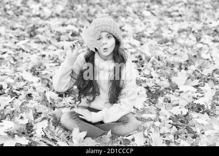 Hat tenere in caldo. Usura del capretto morbido Caldo berretto lavorato a maglia. Allegro. Caldo accessorio di lana. Ragazza capelli lunghi faccia felice rientrano la natura dello sfondo. Tenervi caldi questo autunno. Il bambino nel cappello giallo all'esterno. Foto Stock