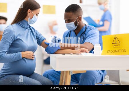 Donna incinta che riceve il vaccino di Coronavirus iniezione Shot in ospedale Foto Stock