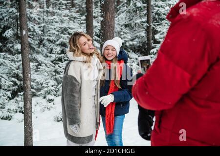 Durante una passeggiata nella foresta invernale, un padre scatta foto di una madre e di una figlia su uno smartphone. Foto Stock