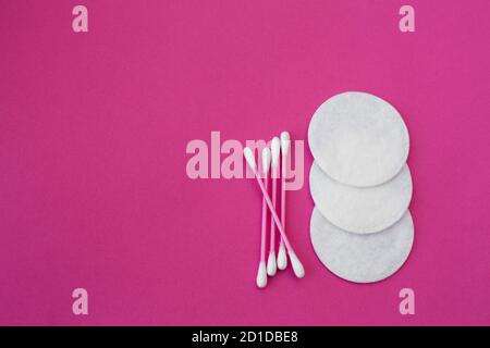 Vista dall'alto sulla rosa batuffoli di cotone con teste di bianco e bianco round dischetti in cotone steso su un sfondo rosa. Foto Stock