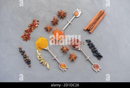 Vista dall'alto di spezie brillanti in cucchiai d'argento vintage come ingrediente per un pasto gustoso su sfondo grigio in cemento. Copia spazio per il testo. Foto Stock