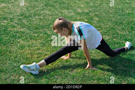 fitness, sport, allenamento, persone e concetto di esercizio - ragazza adolescente facendo splits. allenamento all'aperto e stretching. Foto Stock