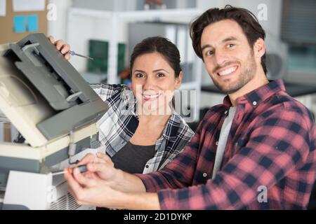 felici due lavoratori e la manutenzione della stampante Foto Stock