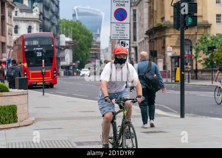 LONDRA, INGHILTERRA - 3 GIUGNO 2020: Anziano ciclista maschile in bicicletta a Holborn Londra indossando una maschera facciale, occhiali e casco durante il COVID Foto Stock