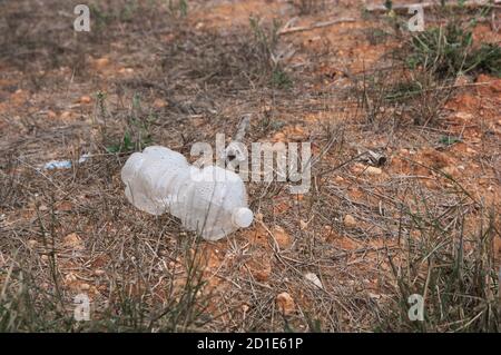 Spazzatura sotto forma di una bottiglia di plastica trasparente che rende l'ambiente sporco degradando nel tempo Foto Stock