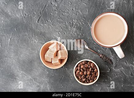 caffè bianco piatto in una tazza. cubetti di zucchero e chicchi di caffè marroni su un tavolo. tempo di relax. vista dall'alto. disposizione piatta Foto Stock