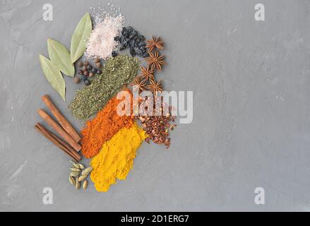 spezie su sfondo grigio. composizione festiva fatta di cannella, pepe, anice, cardamon e sale rosa. spazio per testi o pubblicità. spezie asiatiche o condimento indiano. Foto Stock