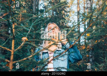 Lo sguardo della ragazza attraverso il fogliame nei boschi. Foto Stock