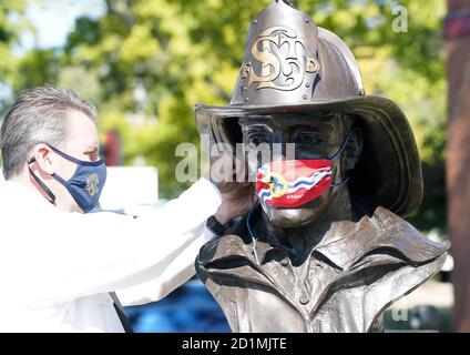 St. Louis, Stati Uniti. 05 ottobre 2020. Il capo del fuoco di St. Louis Dennis Jenkerson assicura una maschera della bandiera di St. Louis City su una statua del pompiere a St. Louis lunedì 5 ottobre 2020. Il Dipartimento del fuoco di St. Louis sta assistendo la Camera di Commercio di St. Louis Arts, installando rivestimenti per il viso a tutte le statue nella zona di St. Louis, spingendo il messaggio di indossare maschere per fermare la diffusione del Covid-19. Photo by Bill Greenblatt/UPI Credit: UPI/Alamy Live News Foto Stock