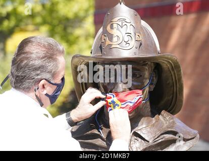 St. Louis, Stati Uniti. 05 ottobre 2020. Il capo del fuoco di St. Louis Dennis Jenkerson assicura una maschera della bandiera di St. Louis City su una statua del pompiere a St. Louis lunedì 5 ottobre 2020. Il Dipartimento del fuoco di St. Louis sta assistendo la Camera di Commercio di St. Louis Arts, installando rivestimenti per il viso a tutte le statue nella zona di St. Louis, spingendo il messaggio di indossare maschere per fermare la diffusione del Covid-19. Photo by Bill Greenblatt/UPI Credit: UPI/Alamy Live News Foto Stock