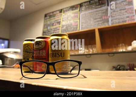 Lattine di birra giapponesi (Kirin, Suntory, Yebisu) e occhiali. Foto Stock