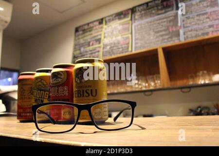 Lattine di birra giapponesi (Kirin, Suntory, Yebisu) e occhiali. Foto Stock