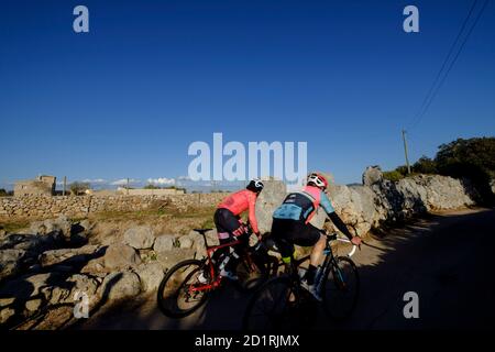 Ciclista frente la muralla de un poblado talayótico, es Pou Celat (Salat), Maiorca, isole baleari, Spagna Foto Stock