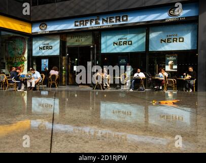 Le persone si siedono all'esterno di un caffè Nero food Catena di negozi al dettaglio nel centro di Londra con segnaletica blu Foto Stock