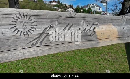St. Moritz, Graubünden, Svizzera - 30 settembre 2020 : insegna di St. Moritz incisa su una panchina di legno con case cittadine sullo sfondo. St. Moritz Foto Stock