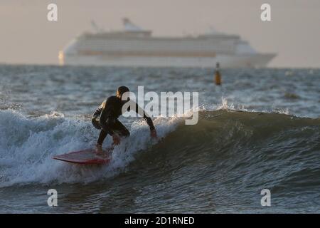 Un surfista corre un'onda nel mare al largo della spiaggia di Boscombe in Dorset. Foto Stock