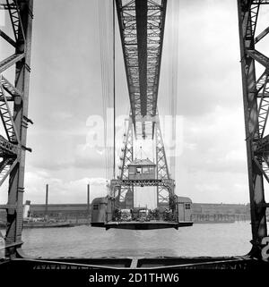 TRANSPORTER BRIDGE, Middlesbrough, Cleveland. Questo ponte di trasporto è uno dei quattro in Gran Bretagna. Costruita nel 1911, una piattaforma mobile è stata assestata da cavi di un telaio in acciaio e ha trasportato passeggeri e veicoli attraverso i River Tees. Questo progetto è stato scelto per ridurre al minimo le interruzioni della spedizione. Fotografato da Eric de Mare nel 1955. Foto Stock