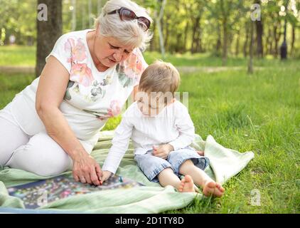 Granny e bambino seduto e giocando giochi da tavolo nel parco estivo Foto Stock
