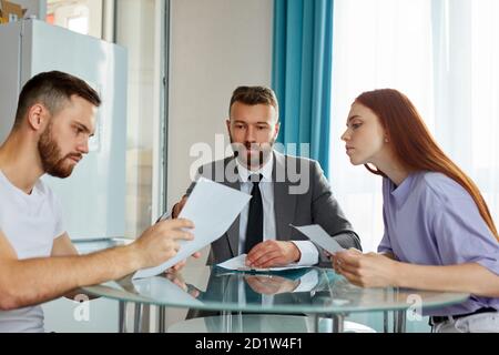 giovane coppia caucasica in visita avvocato professionale, rifiutare di firmare carta decreto e finalizzare divorzio. a matrimonio consulente o agente ufficio. separazione di famiglia, divorzio concetto Foto Stock