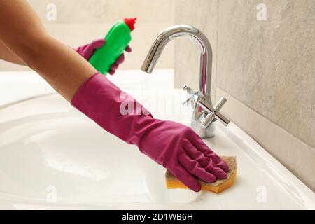 Donna in lavello di pulizia guanto rosa di gomma Foto Stock