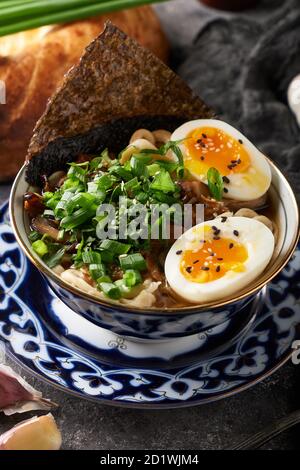 Tradizionale zuppa asiatica di noodle ramen con pollo e uova sfondo grigio Foto Stock