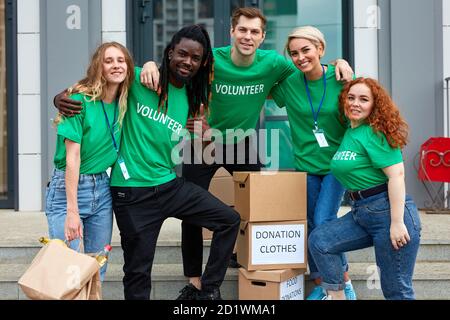 diversi volontari si impacchettano, raccolgono gli aiuti umanitari nella scatola delle donazioni. gruppo multietnico di persone che lavorano in fondazione caritativa per aiutare in crisi e senza tetto Foto Stock