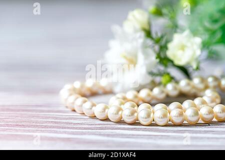 Bella collana di perle bianche con fiori bianchi. Foto Stock