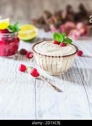 Yogurt greco in una ciotola di ceramica su un tavolo di legno chiaro. Foto Stock