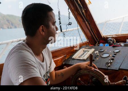 Antalya/Turchia-Settembre 25 2020:Capitano o timoniere su uno yacht o motoscafo che naviga nel Mediterraneo visto da un lato seduto al timone . Foto Stock