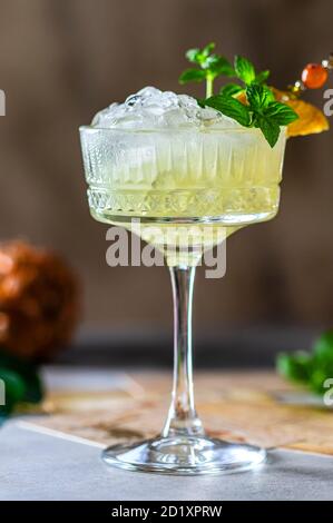 Succo di ananas fresco spremuto con ghiaccio tritato e menta su uno sfondo di cemento grigio chiaro. Foto Stock