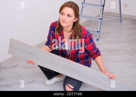 Giovane donna installa pavimenti in laminato in appartamento Foto Stock