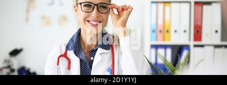 Donna medico con occhiali sorridenti sul posto di lavoro in ufficio medico Foto Stock