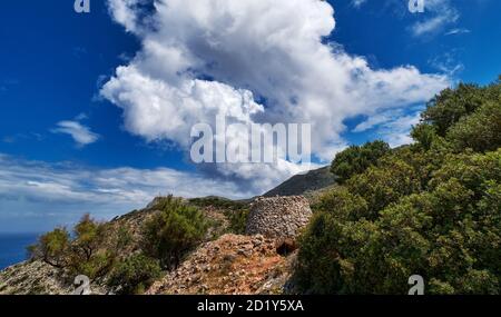 Tipico paesaggio greco, collina, montagna, fogliame primaverile, cespuglio, olivo, sentiero roccioso. Cielo blu con belle nuvole. Akrotiri, la Canea, Creta, Grecia Foto Stock