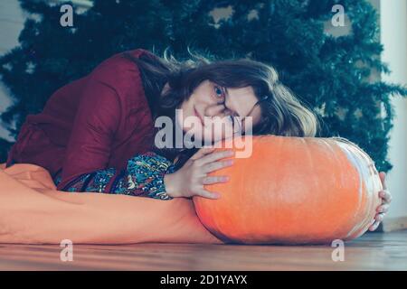 Una donna si trova su una grande zucca sullo sfondo Di un albero di Natale Foto Stock