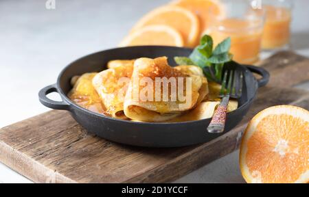 Crepes con salsa di arancia in una padella di ghisa. Suzette tradizionale francese con salsa d'arancia. Foto Stock