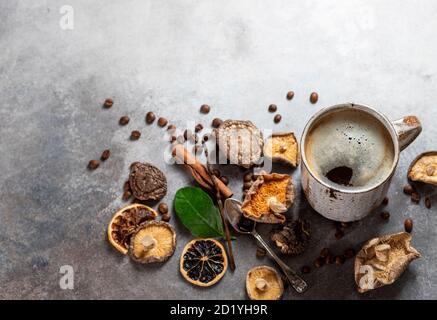 Caffè di funghi, una tazza di ceramica, funghi e chicchi di caffè su fondo di cemento di pietra. Nuova tendenza del superfood. Foto Stock