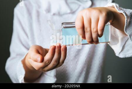 Vista ravvicinata del bambino di 6 anni che utilizza un piccolo igienizzatore portatile antibatterico per le mani. Foto Stock