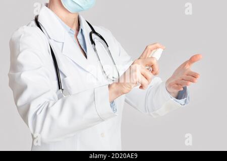 Protezione da virus, medicina e assistenza sanitaria. Signora medico disinfetta le mani con antisettico Foto Stock