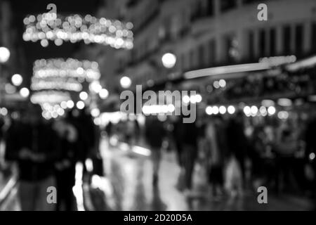 Foto sfocata di Montorgueil Street a Parigi di notte con bella decorazione di luci di Natale e la folla della gente. Vacanze invernali viaggio. Bianco nero Foto Stock