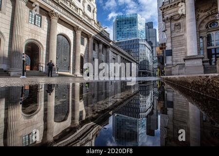 Bank of England, e Royal Exchange si sono riflesse in un pozze dopo le forti tempeste di pioggia nella City of London, Threadneedle Street, Inghilterra, Regno Unito Foto Stock