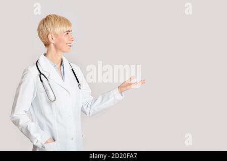 Assistenza sanitaria, professionisti medici e visita al medico. Punte femminili amichevoli con la mano nello spazio vuoto Foto Stock