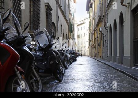 Piccolo vicolo con una fila di motociclette parcheggiate a Firenze, Italia Foto Stock