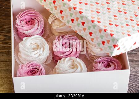 scatola bianca con zephyr fatto in casa rosa e bianco su grigio sfondo di legno Foto Stock