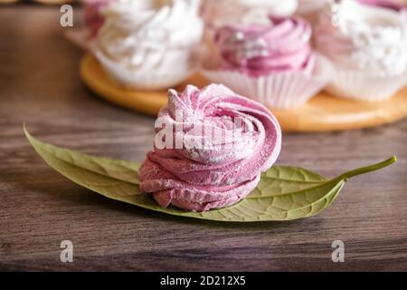 marshmallow fatti in casa rosa e bianco (zephyr) su una tavola rotonda di legno su uno sfondo grigio di legno. Foto Stock