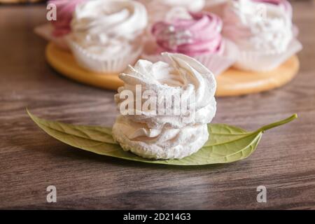 marshmallow fatti in casa rosa e bianco (zephyr) su una tavola rotonda di legno su uno sfondo grigio di legno. Foto Stock