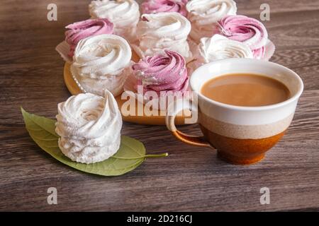 marshmallow fatti in casa rosa e bianco (zephyr) su una tavola rotonda di legno su uno sfondo grigio di legno. Foto Stock