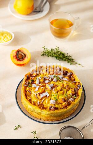 Deliziosa torta al chiffon con crema pasticcera e nettarine con tè alle erbe e timo su fondo di cemento chiaro. Foto Stock