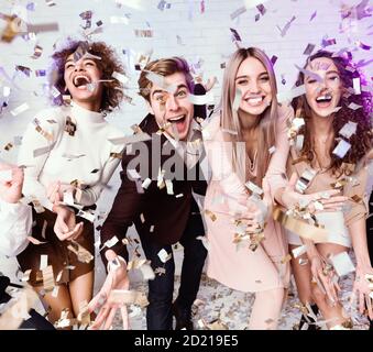 Amici multietnici che si divertono a vivere festeggiando con Falling Confetti Indoor Foto Stock